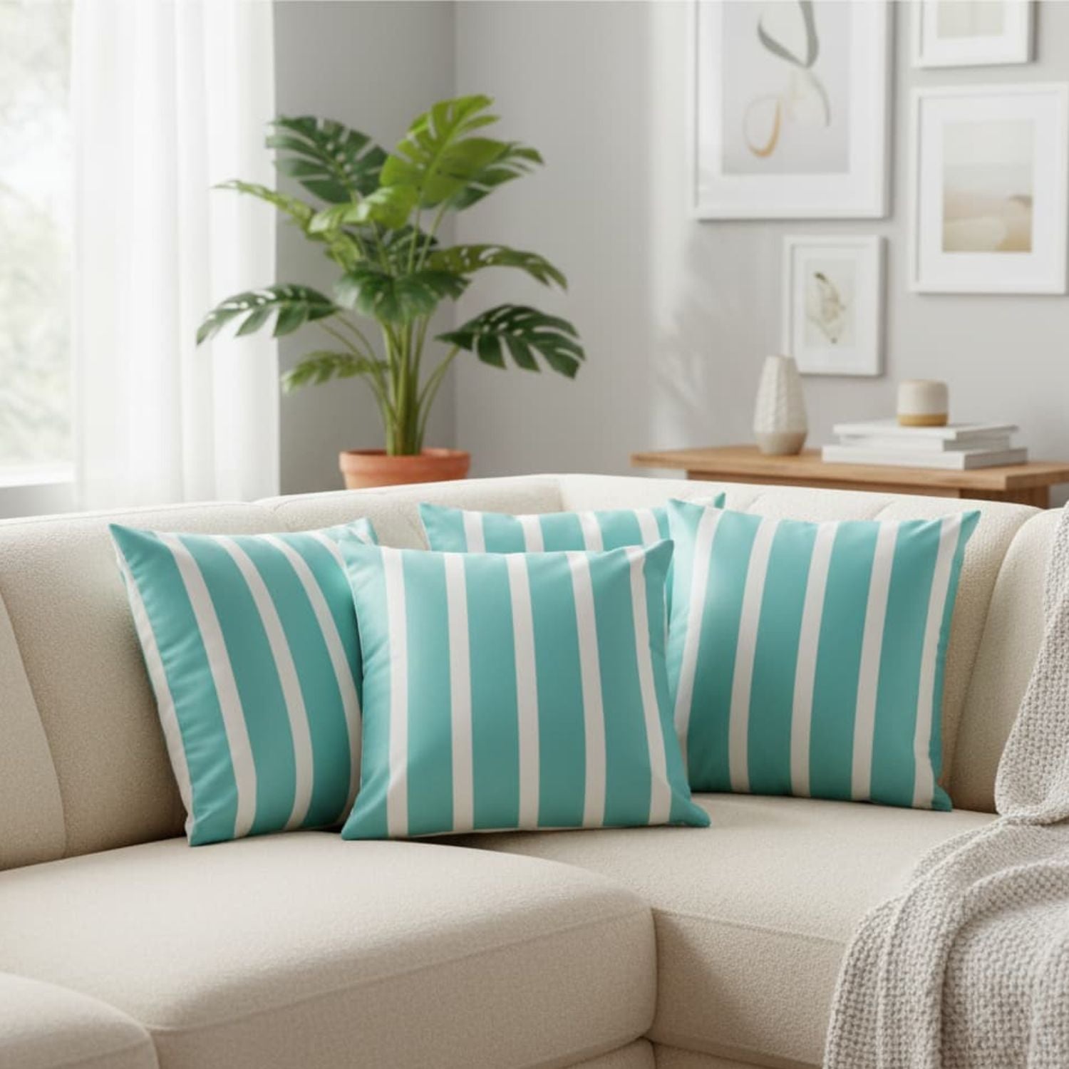 Loosebucket Teal and white striped pillows on a beige sofa in a living room with a plant and books in the background.
