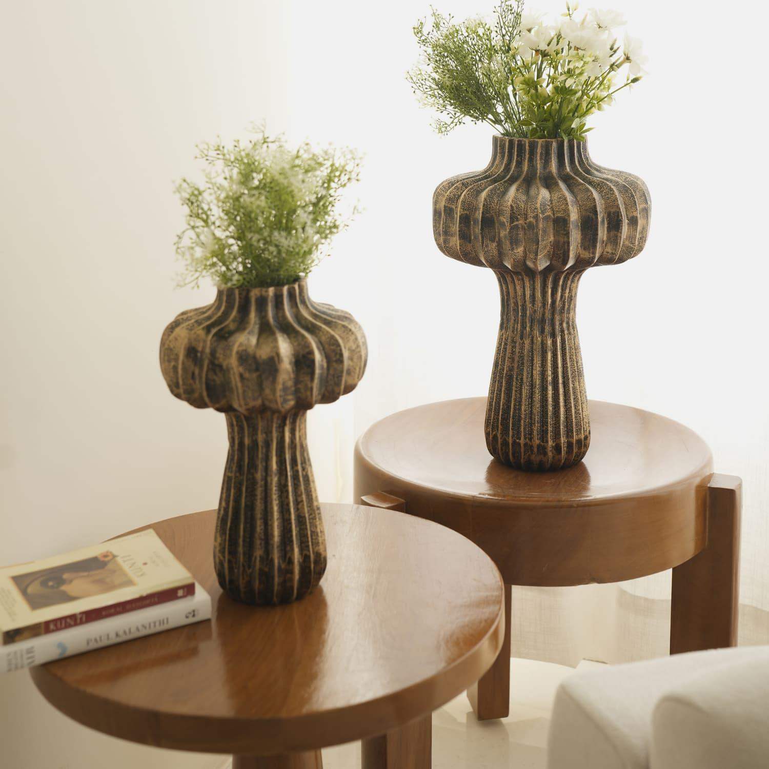 Premium Vintage Portobello Aluminum Vases displayed on wooden side tables, featuring two mushroom-shaped vases in antique golden brown finish with ribbed texture, holding delicate white and green floral arrangements. Taller vase measures 16 inches, shorter 12 inches.