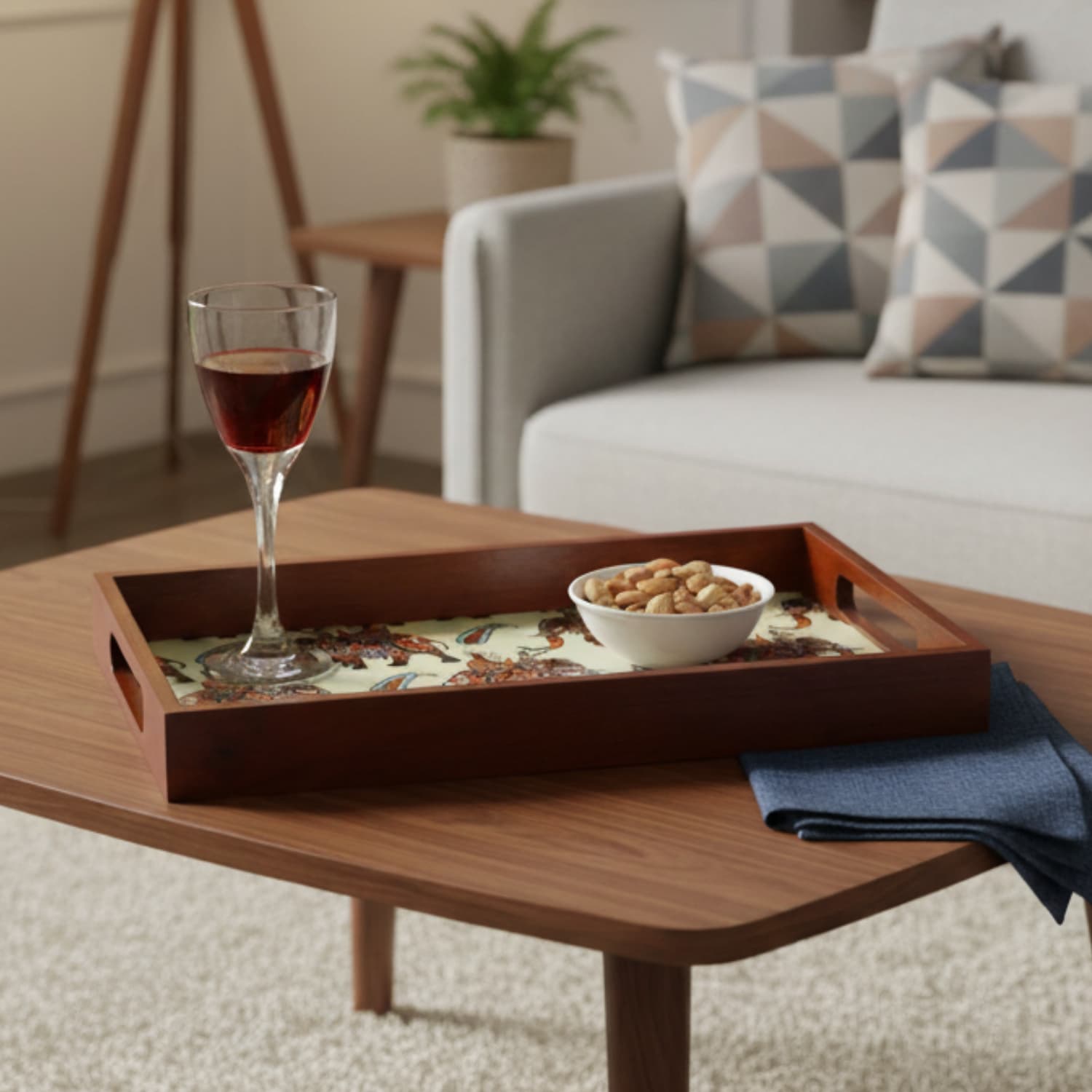Loosebucket Walking Elephant Wooden tray  with a glass of red wine and bowl of nuts on a coffee table in a living room.