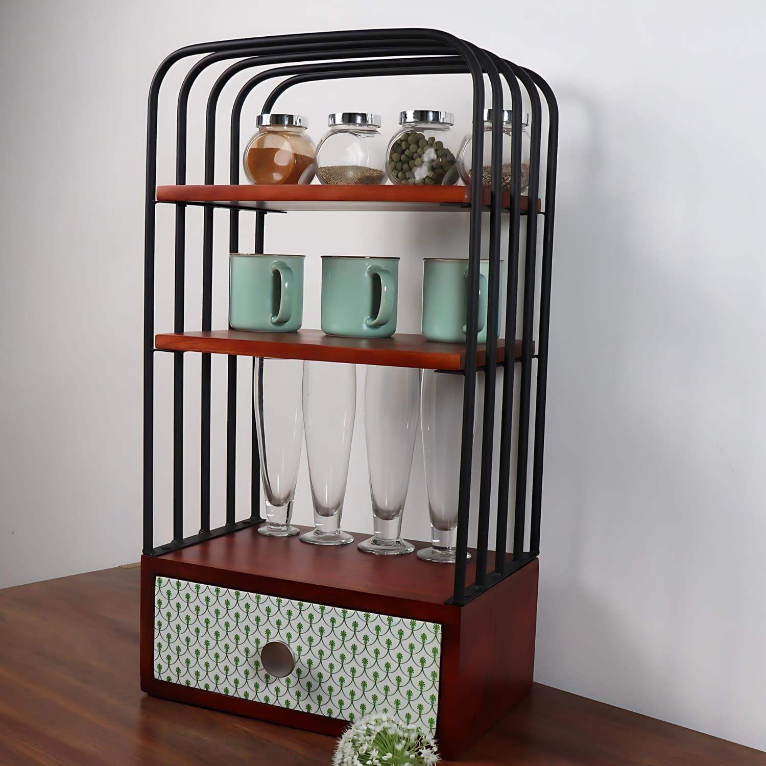 Loosebucket Green Bellezza wooden kitchen organizer featuring black metal frame, three walnut brown shelves displaying glass jars, mint green mugs, and tall glasses, with a decorative pattern drawer at base. Modern rustic design perfect for kitchen storage and organization.