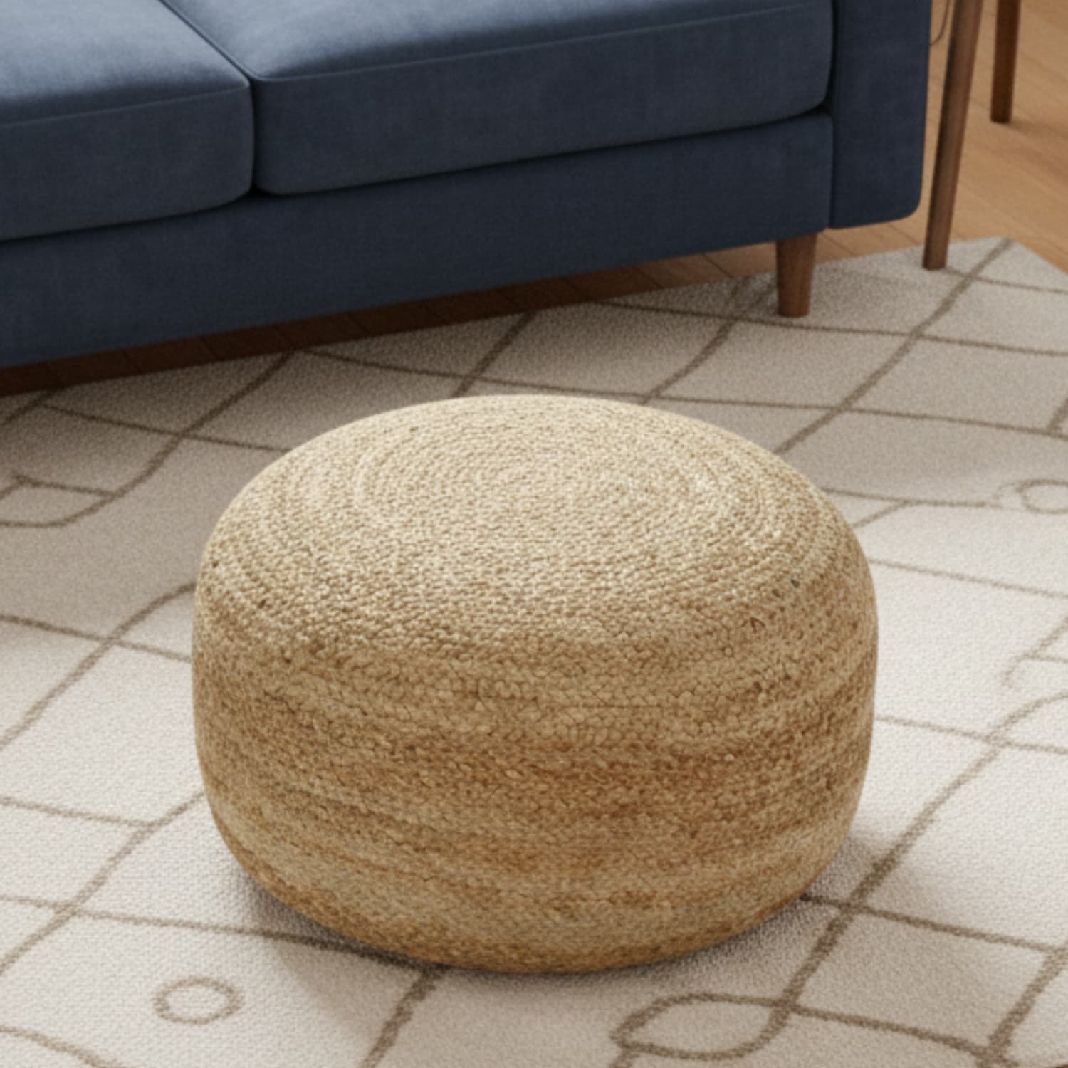 Loosebucket Beige woven ottoman on a patterned rug with a blue sofa in the background
