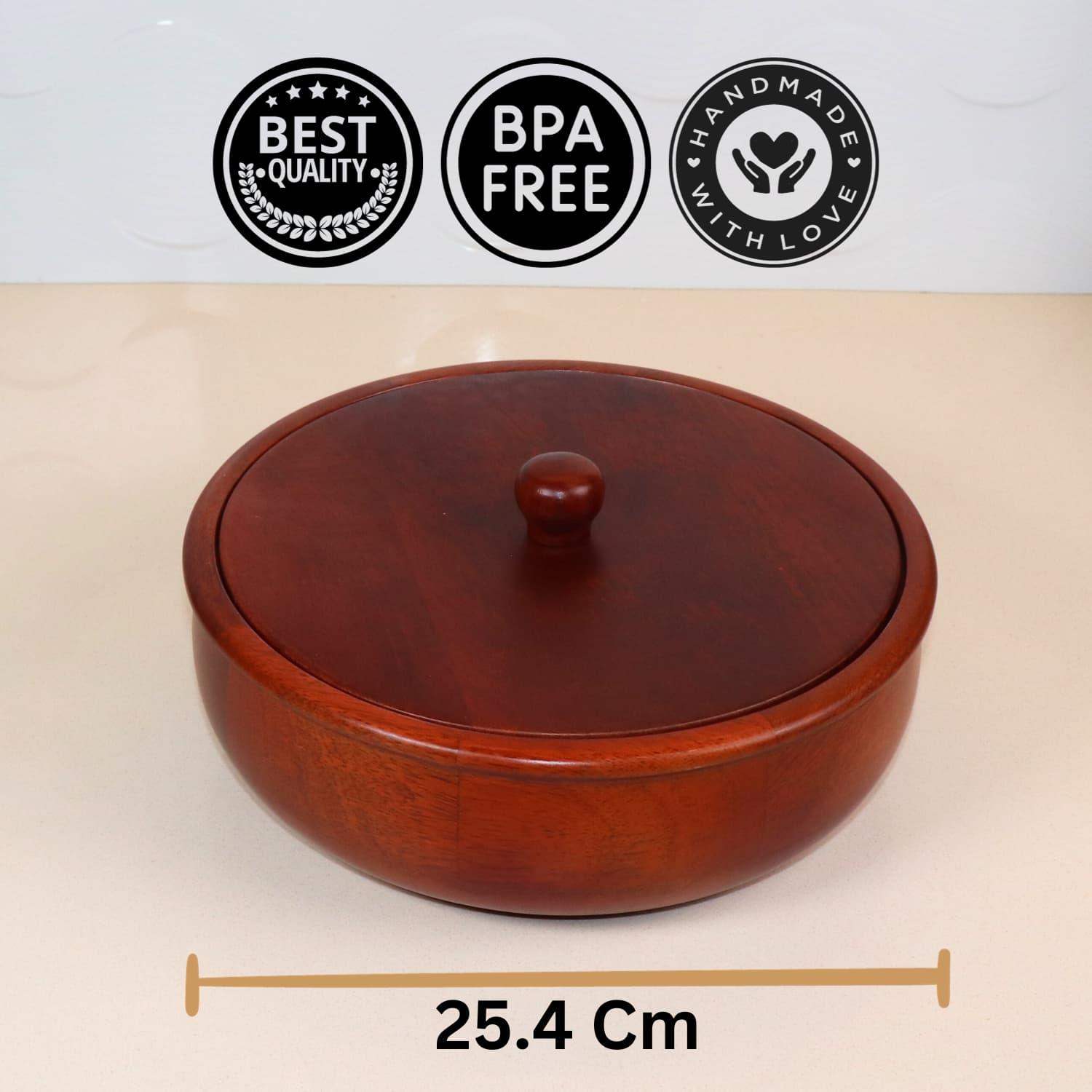 A round, wooden container with a matching lid featuring a knob handle, placed on a light-colored surface. Above the best wooden chapati box in India, there are three icons labeled "Best Quality," "BPA Free," and "Handmade with Love." Below the container, a measurement reads "25.4 cm." This is The Woody Casserole Chapati box by LOOSEBUCKET.